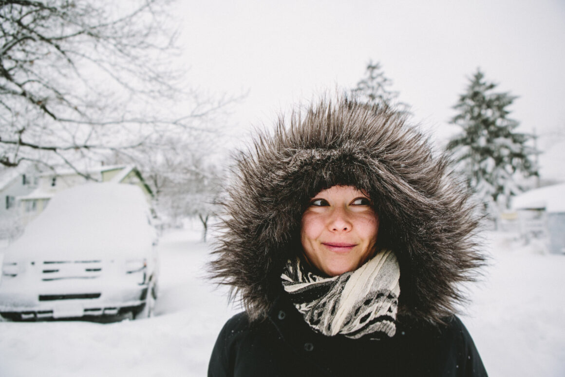 Woman in fur lined parka in snow.
