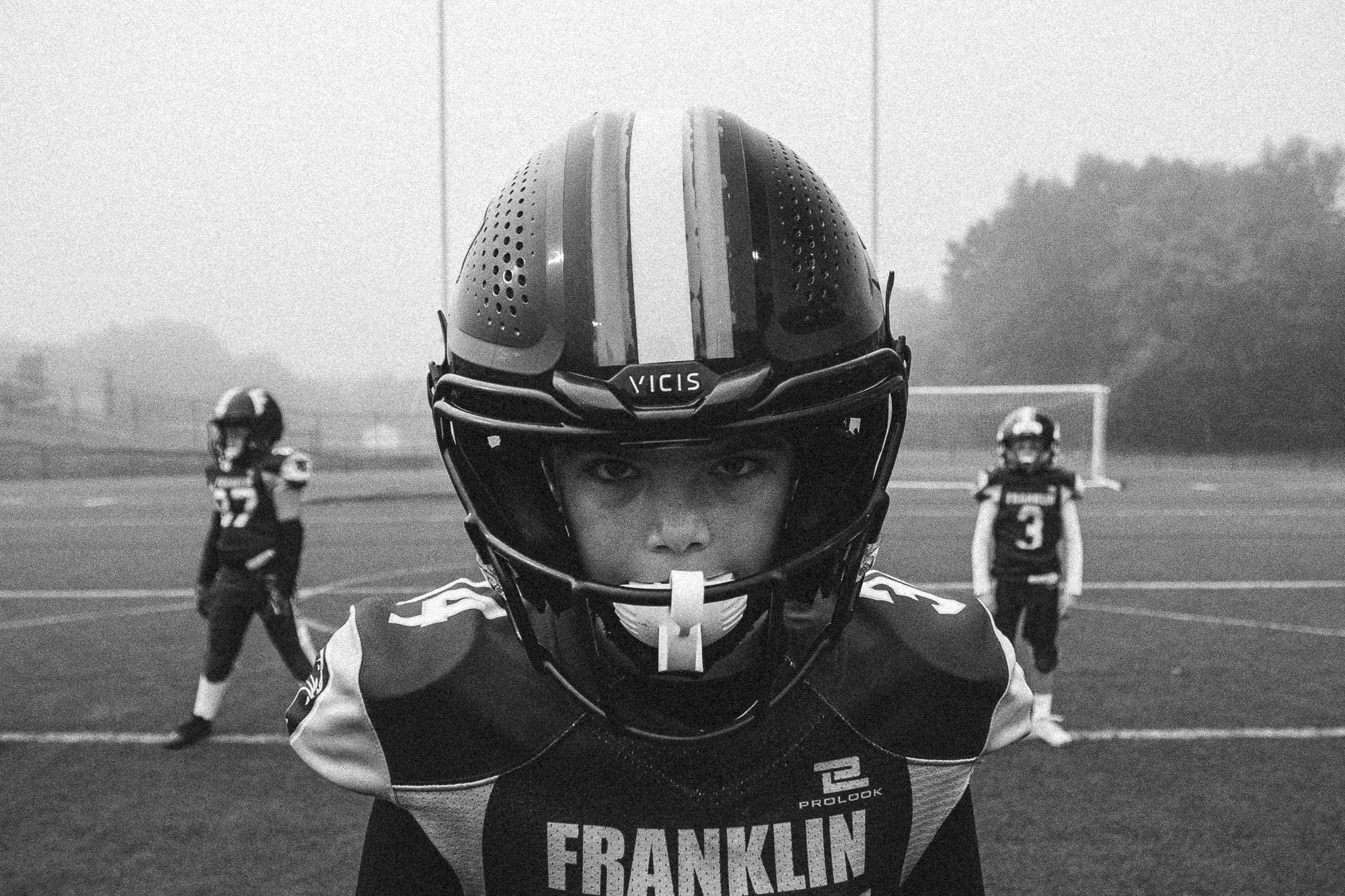 Franklin Panthers youth football player Callan in helmet and uniform, intense pre-game focus on the field in Franklin, MA